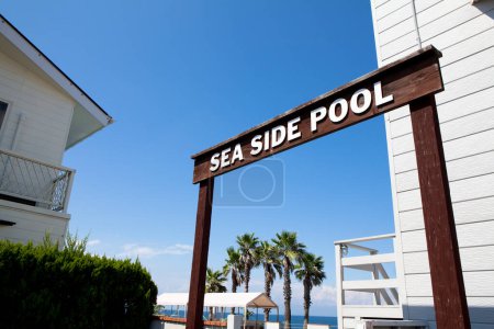 Téléchargez les photos : Le signe de la piscine côté mer contre le ciel bleu - en image libre de droit