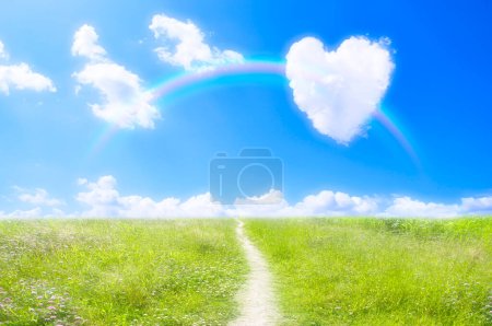 Photo for Heart shaped clouds and rainbow on blue sky over green field - Royalty Free Image