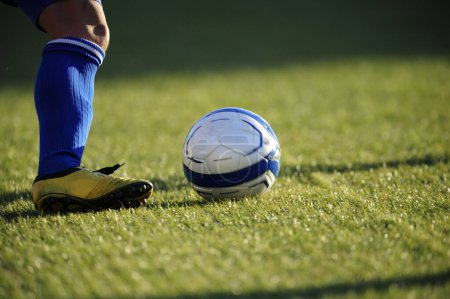 Téléchargez les photos : Jambe des sportifs en vêtements de sport jouer au football sur l'herbe - en image libre de droit