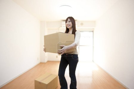 Téléchargez les photos : Heureux asiatique femme se déplaçant dans maison, tenant boîte en carton - en image libre de droit