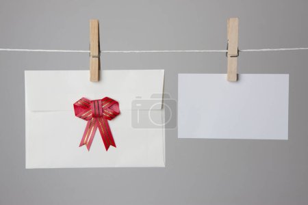 Foto de Tarjeta blanca en blanco y sobre colgando en la cuerda con clavijas de ropa, espacio de copia. - Imagen libre de derechos