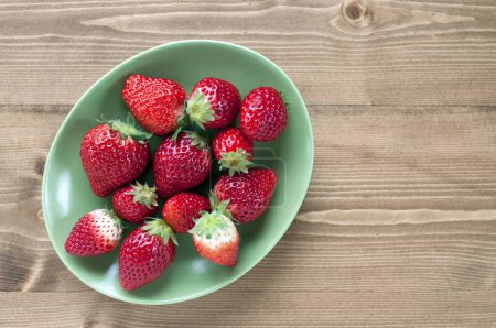Photo for Bowl of strawberries on a wooden table - Royalty Free Image