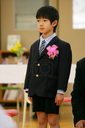 Photo for Cute preteen Japanese boy in school wearing suit decorated with pink bow - Royalty Free Image