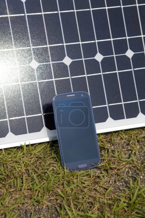 Photo for Smartphone and solar panel on green grass - Royalty Free Image