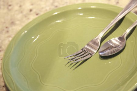 Foto de Tenedor y cuchara en plato verde vacío - Imagen libre de derechos
