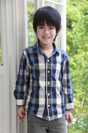 Photo for Portrait of a smiling Asian preteen boy posing in backyard of his house - Royalty Free Image