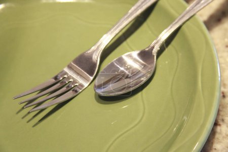 Photo for Fork and spoon on empty green plate - Royalty Free Image