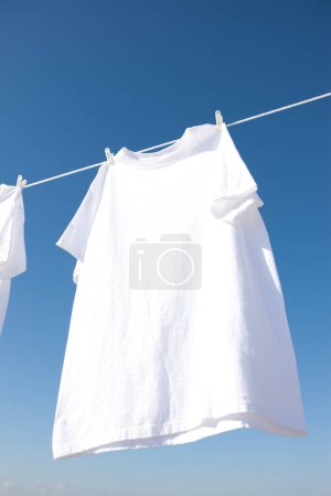 Photo for Tshirt on clothespins against the blue sky - Royalty Free Image