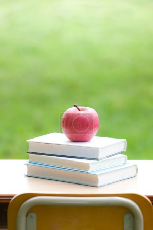 Photo for Apple on stack of books on table outdoors - Royalty Free Image