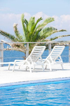 Téléchargez les photos : Piscine vide avec chaises longues et vue sur la mer bleue - en image libre de droit