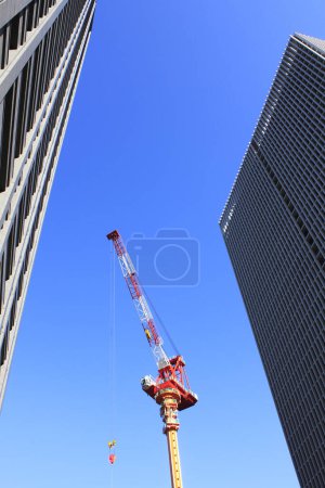 Téléchargez les photos : Vue à angle bas de l'architecture moderne et la grue du chantier de construction sur fond de ciel bleu - en image libre de droit