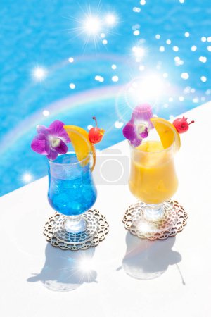 Photo for Glasses and cocktails with flowers on the background of pool with sun rays and rainbow - Royalty Free Image