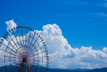 Foto de Una noria y una montaña con cielo azul y nubes en el fondo - Imagen libre de derechos