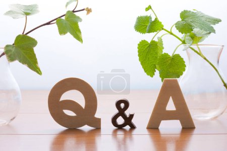 Téléchargez les photos : Q et un symbole sur une table en bois. concept des réponses aux questions. Plantes vertes dans des vases - en image libre de droit