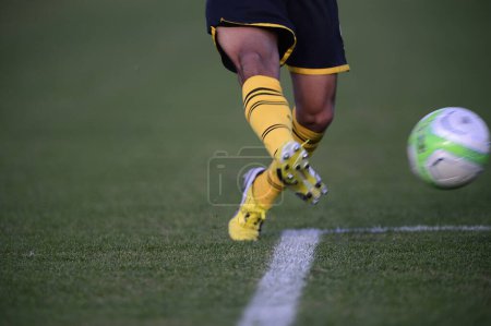 Photo for A soccer player kicking a soccer ball on a field - Royalty Free Image