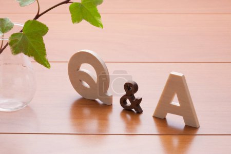 Téléchargez les photos : Q et un symbole sur une table en bois. concept des réponses aux questions. Plante verte en vase - en image libre de droit