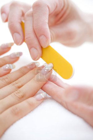 Foto de Cerrar la imagen de la manicura utilizando la lima de uñas para dar forma a las uñas de los dedos en el salón de cosméticos - Imagen libre de derechos
