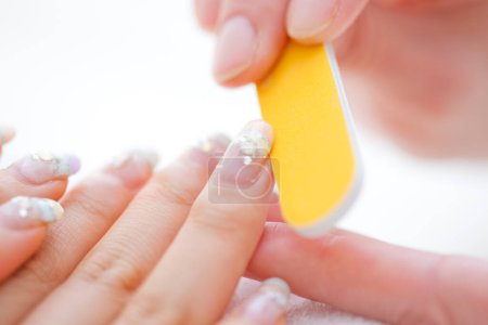 Téléchargez les photos : Image rapprochée de manucure à l'aide de lime à ongles pour façonner les ongles des doigts dans le salon cosmétique - en image libre de droit