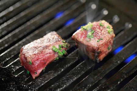 Téléchargez les photos : Steaks de bœuf sur le gril aux herbes et épices. - en image libre de droit