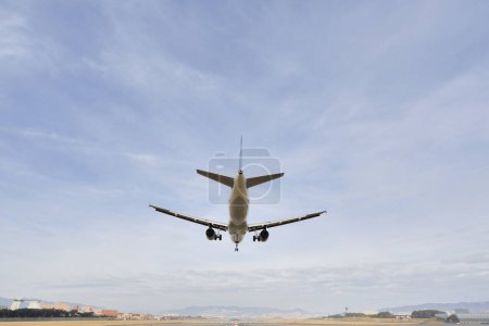 Téléchargez les photos : Avion atterrissant sur le fond d'un ciel bleu avec des nuages - en image libre de droit