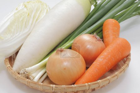 Foto de Cesta de verduras incluyendo zanahorias, cebollas, nabo chino y col de napa - Imagen libre de derechos