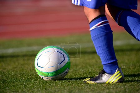 Téléchargez les photos : Un footballeur donnant un coup de pied à un ballon de football sur un terrain - en image libre de droit