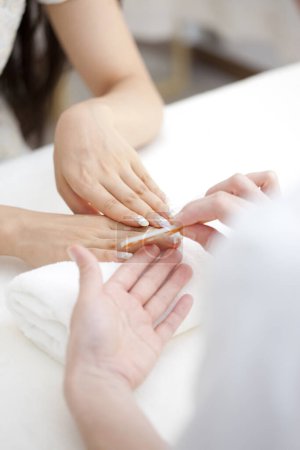 Photo for Close up image of manicurist using nail file to shape finger nails in cosmetic salon - Royalty Free Image