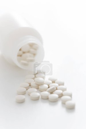 Téléchargez les photos : Vue rapprochée des pilules en bouteille sur fond blanc - en image libre de droit