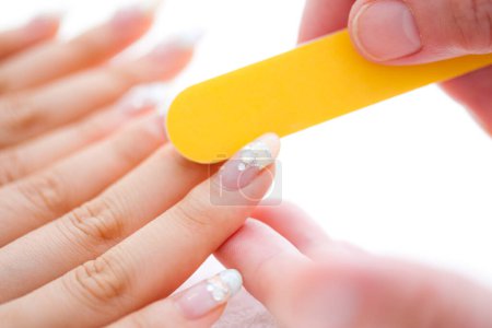 Photo for Close up image of manicurist using nail file to shape finger nails in cosmetic salon - Royalty Free Image