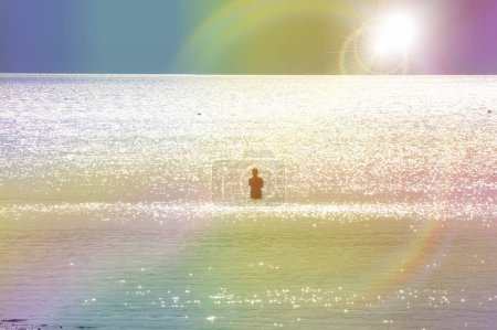 Téléchargez les photos : Un homme se tient en mer pendant le coucher du soleil - en image libre de droit