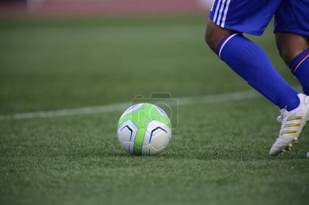 Téléchargez les photos : Un footballeur donnant un coup de pied à un ballon de football sur un terrain - en image libre de droit