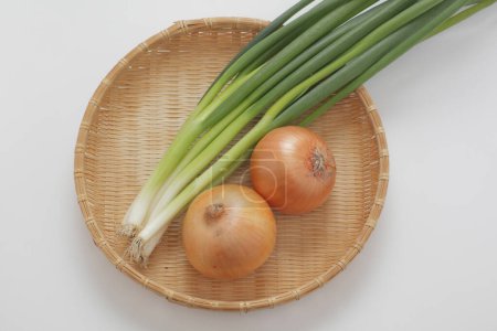 Téléchargez les photos : Plat en osier avec bouquet d'oignons sur fond blanc, vue de dessus - en image libre de droit