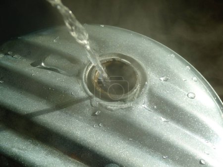 Foto de Verter agua caliente en un recipiente de metal - Imagen libre de derechos
