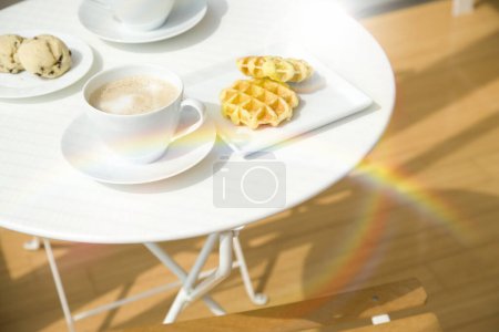 Photo for Coffee cup and croissant with sun rays on wooden table - Royalty Free Image