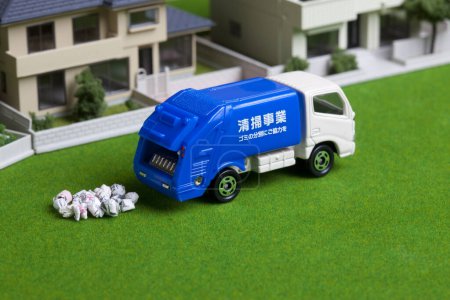 Foto de Camión de basura en miniatura recogiendo basura cerca de modelos de casa - Imagen libre de derechos