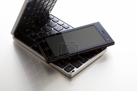 Téléchargez les photos : Vue rapprochée du clavier de l'ordinateur et du téléphone portable sur fond blanc - en image libre de droit