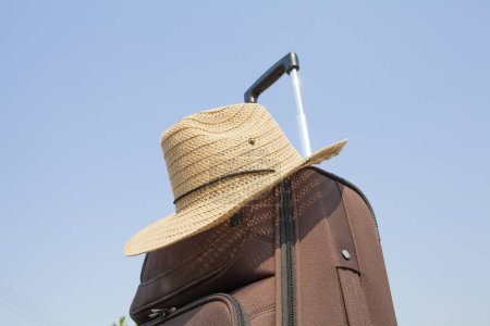 Téléchargez les photos : Valise avec chapeau de paille contre ciel bleu, concept voyage et vacances. - en image libre de droit
