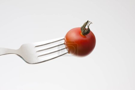 Photo for Red tomato with fork on white background - Royalty Free Image
