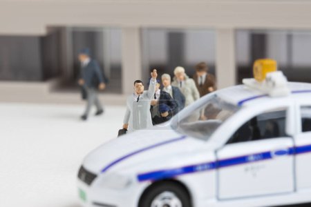 Photo for Miniature businessman catching taxi at station building - Royalty Free Image