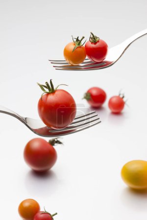 Téléchargez les photos : Tomates biologiques fraîches mûres avec fourchettes sur fond clair - en image libre de droit