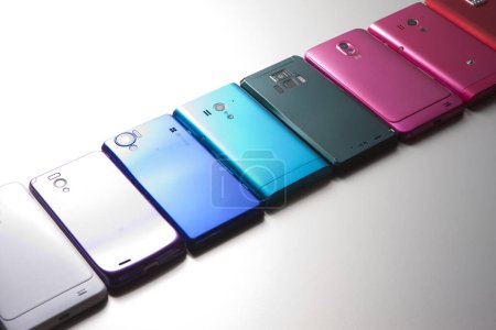 Foto de Vista de cerca de diferentes teléfonos móviles modernos de colores sobre fondo gris - Imagen libre de derechos