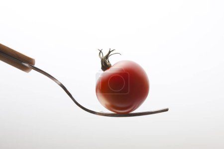 Photo for Red tomato with fork on white background - Royalty Free Image