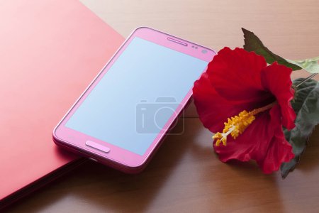 Foto de Flor de hibisco rojo y teléfono inteligente sobre fondo de color - Imagen libre de derechos