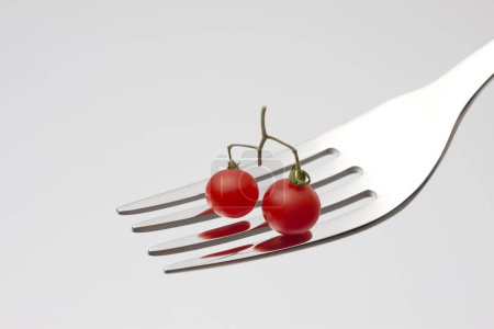 Photo for Red tomatoes with fork on white background - Royalty Free Image