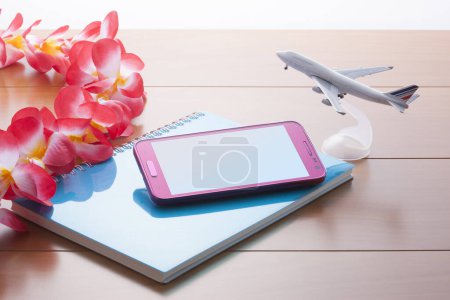 Téléchargez les photos : Téléphone portable avec avion jouet sur table en bois. concept de voyage - en image libre de droit