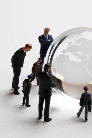 Téléchargez les photos : Gens d'affaires miniatures avec globe en verre sur fond blanc. concept d'entreprise - en image libre de droit