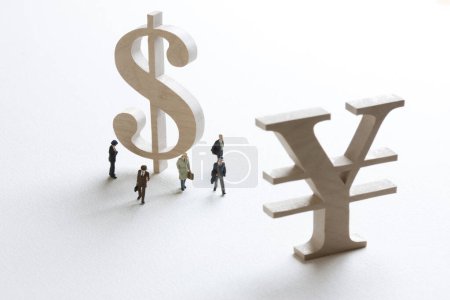 Foto de Figuras en miniatura de hombres de negocios de pie cerca de signos de yen y dólar - Imagen libre de derechos