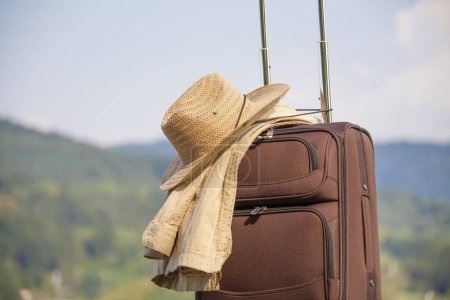 Foto de Maleta con sombrero de paja y chaqueta de pie al aire libre, concepto de viaje - Imagen libre de derechos