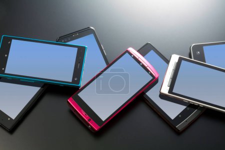 Foto de Teléfonos móviles modernos con diferentes colores sobre fondo oscuro - Imagen libre de derechos