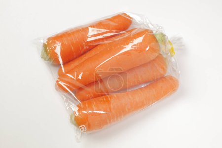 Foto de Bolsa de plástico con zanahorias frescas en blanco - Imagen libre de derechos
